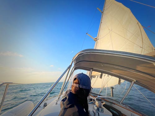 The same sailing photo after the Set Sail template — deep cobalt sky and ocean, warm golden glow at the horizon, crisp rigging, gentle focus vignette